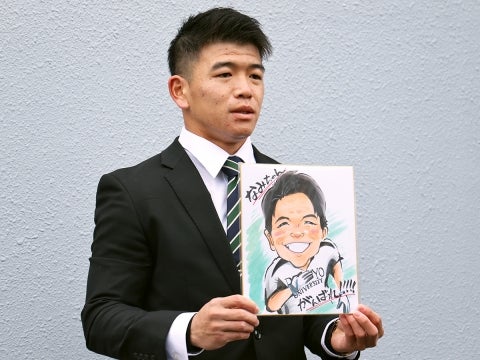 仲間からもらった似顔絵を持って入寮